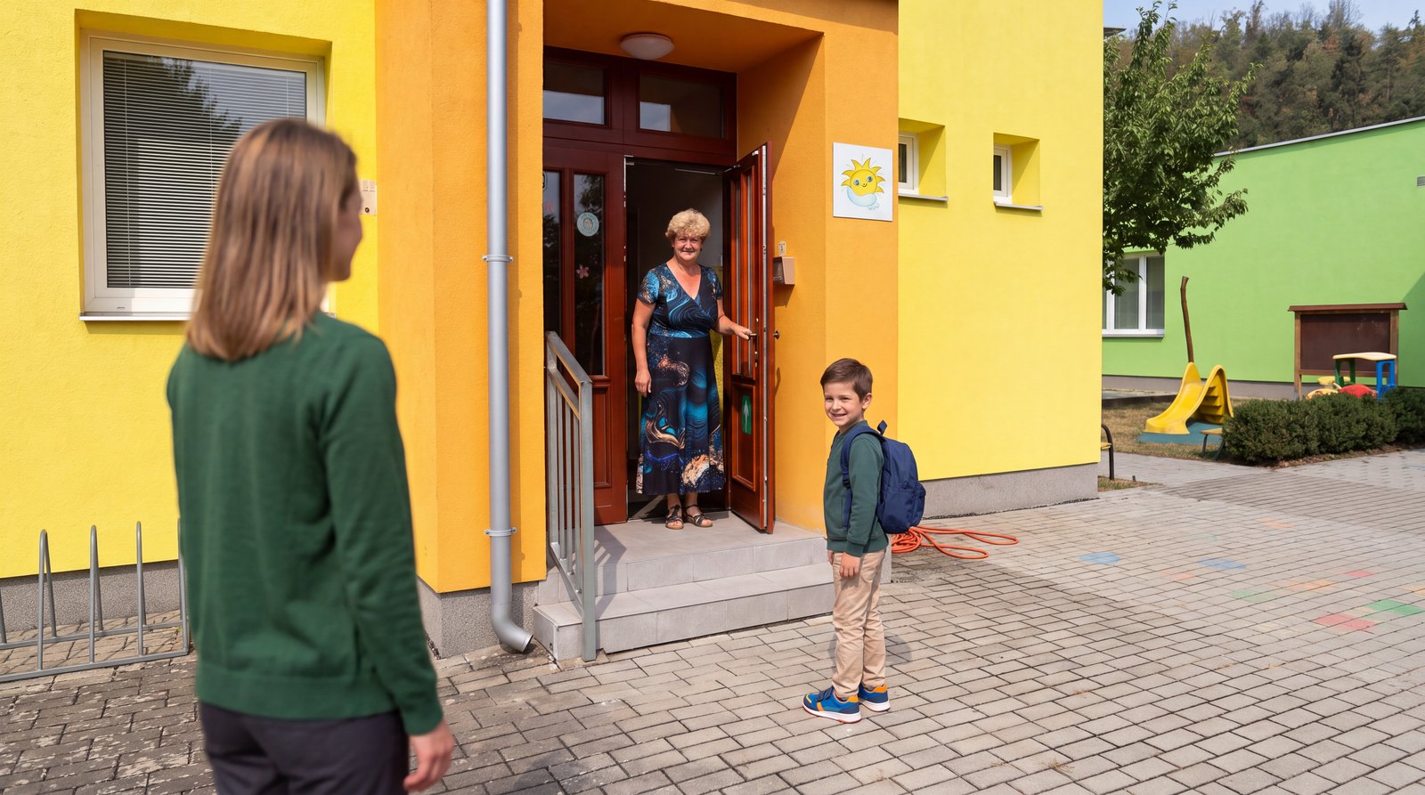 Hotový záběr: paní ředitelka vítá ve dveřích školky kluka s maminkou