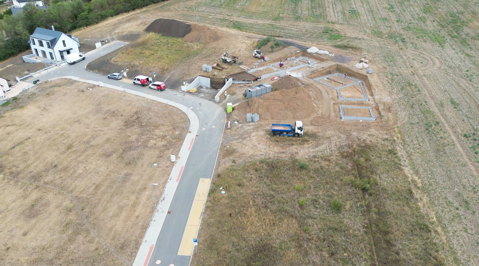 Surová fotka z dronu: parcely a rozestavěná ulice pod zataženou oblohou